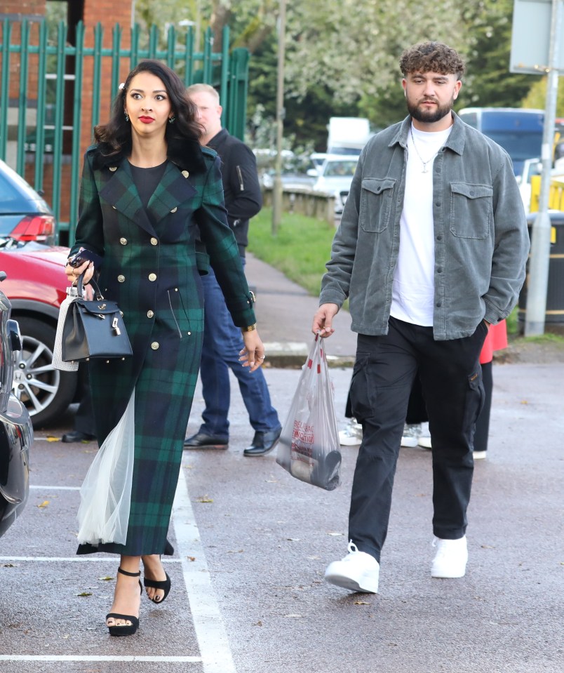 a man and a woman are walking in a parking lot