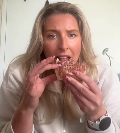 a woman wearing a watch is eating a donut