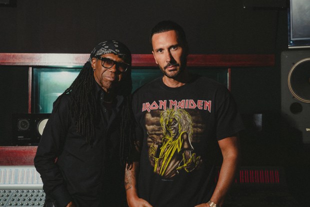 a man wearing an iron maiden shirt stands next to another man