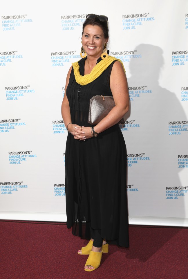 a woman stands in front of a wall that says parkinson 's