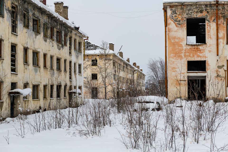 a row of abandoned buildings with snow on the ground