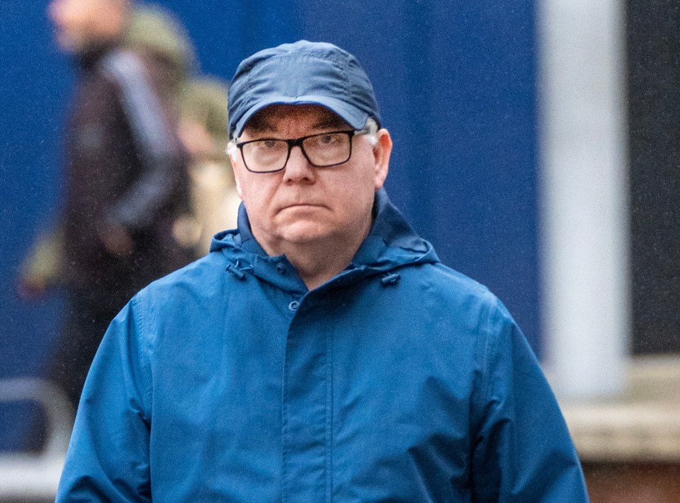 a man wearing glasses and a blue jacket is walking down the street