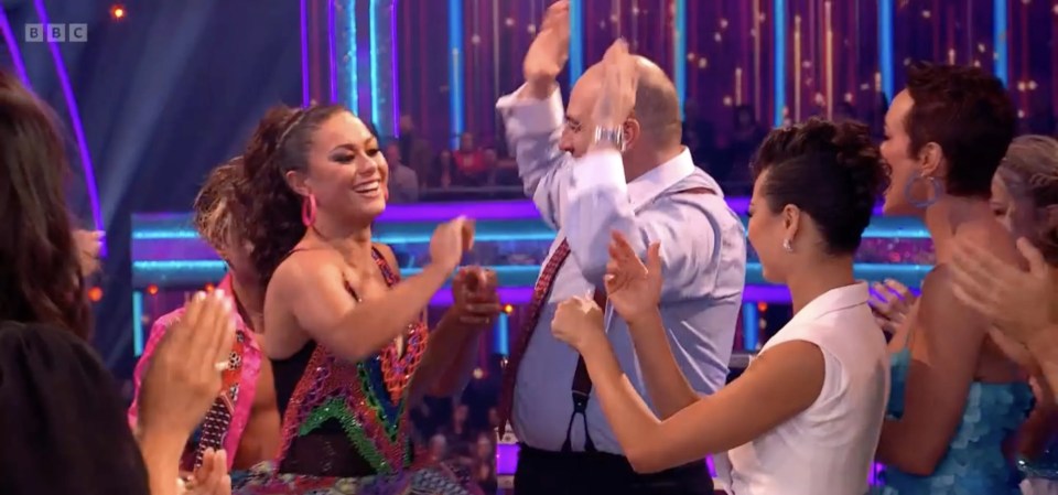 a group of people dancing in front of a screen that says bbc