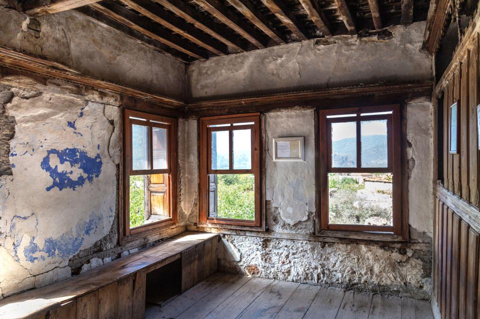 a room with a wooden bench and three windows