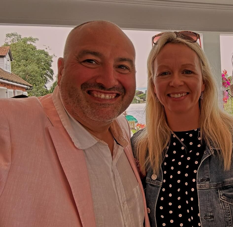 a man in a pink jacket poses with two other people