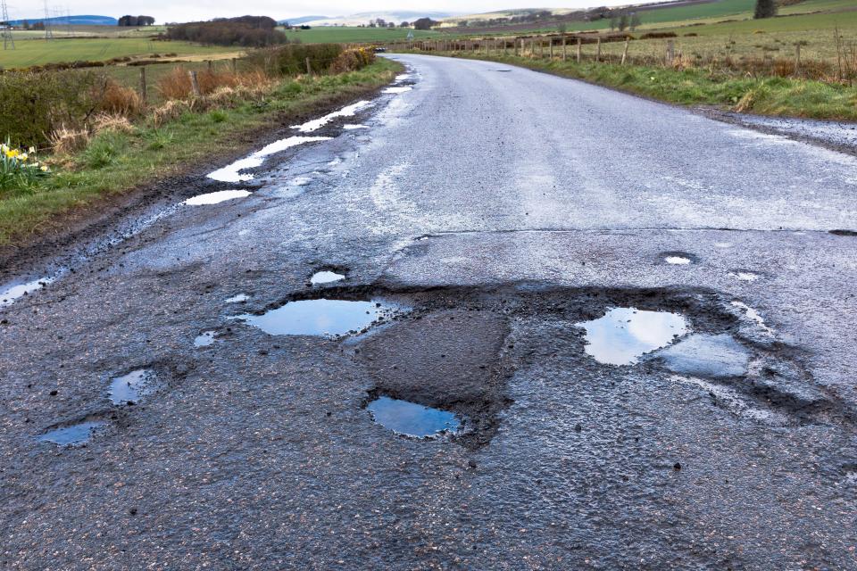 a road with a lot of potholes and puddles on it