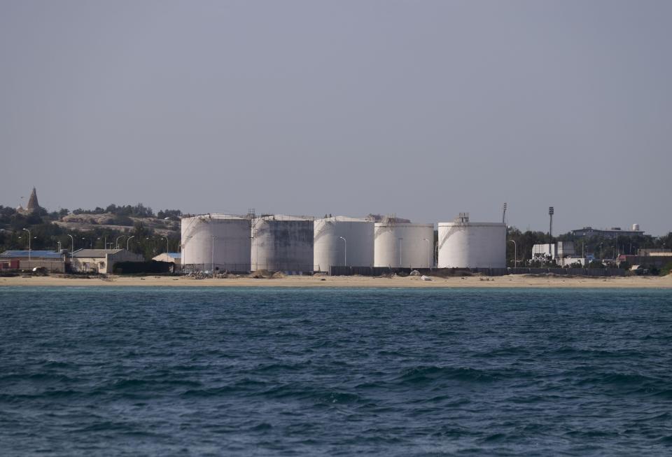 a row of tanks sit on the shore of a body of water