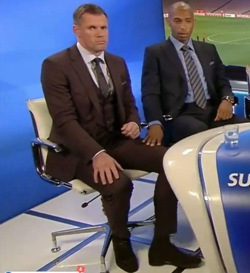 a man in a suit sits next to another man in a suit