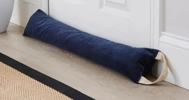 a blue door stopper sits on a wooden floor next to a plant