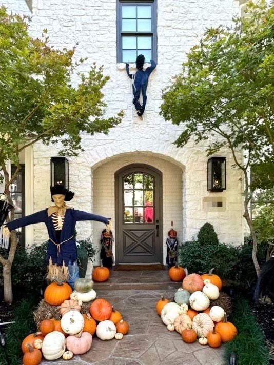 a white house decorated for halloween with pumpkins and scarecrows .