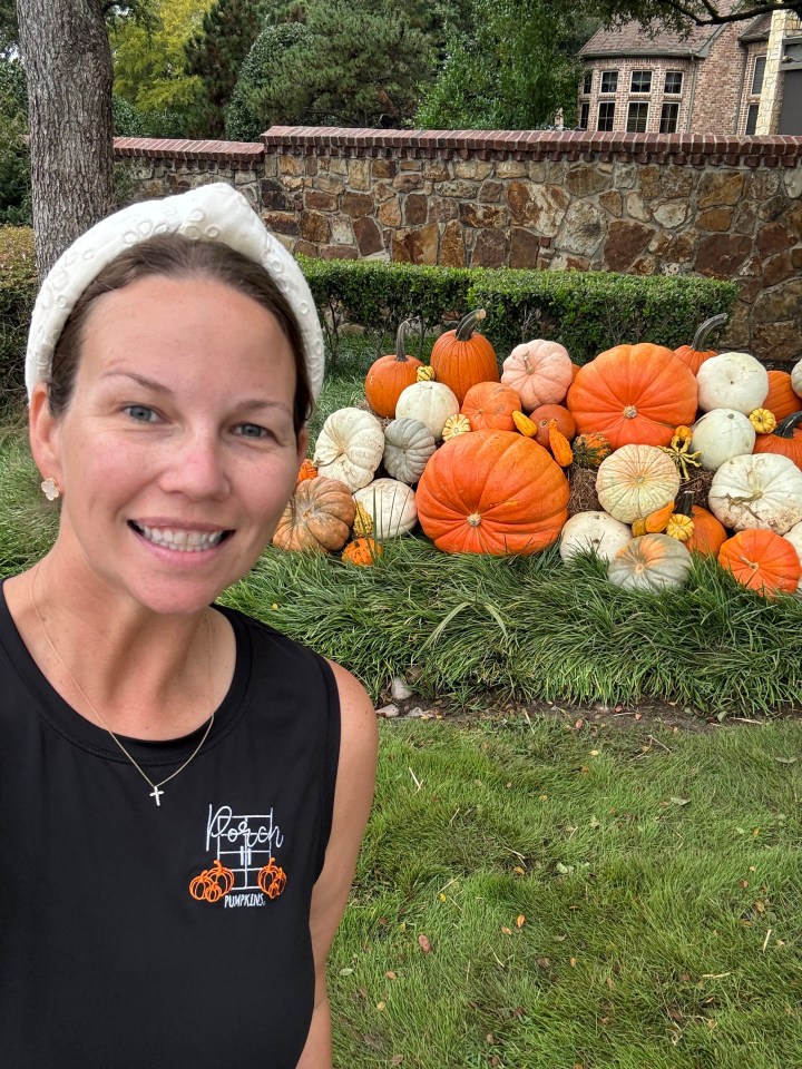 a woman standing in front of a pile of pumpkins wearing a black shirt that says ranch