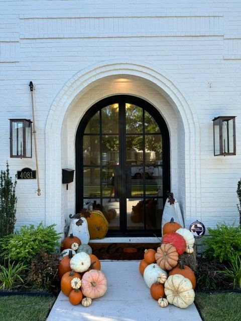 the front door of a white brick house is decorated with pumpkins and lanterns .