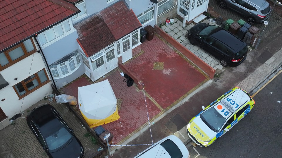 A forensics tent and patrol car are outside the house