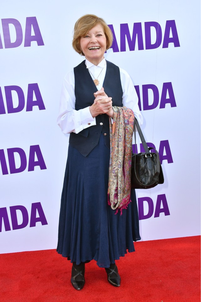 a woman stands on a red carpet in front of a sign that says amda