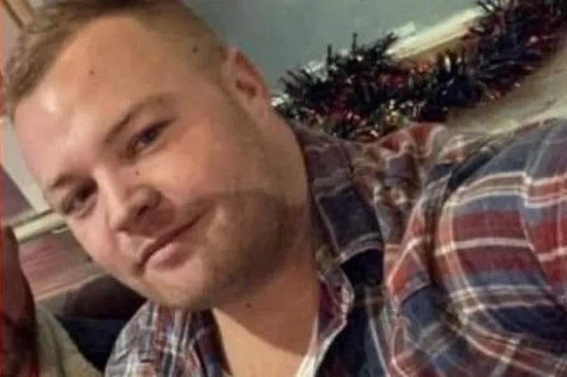 a man in a plaid shirt is taking a selfie in front of a christmas tree .