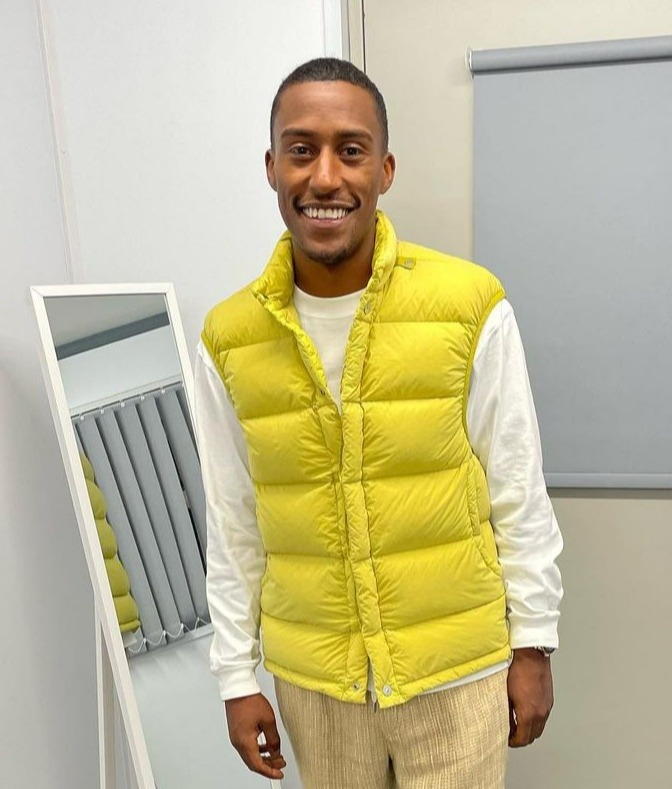 a man in a yellow vest stands in front of a mirror