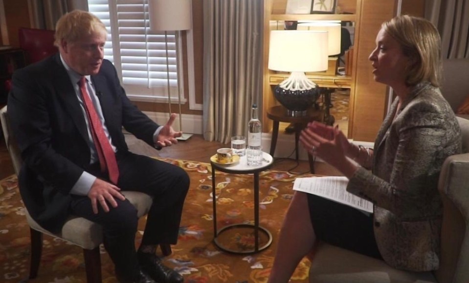 a man in a suit and tie sits in a chair talking to a woman