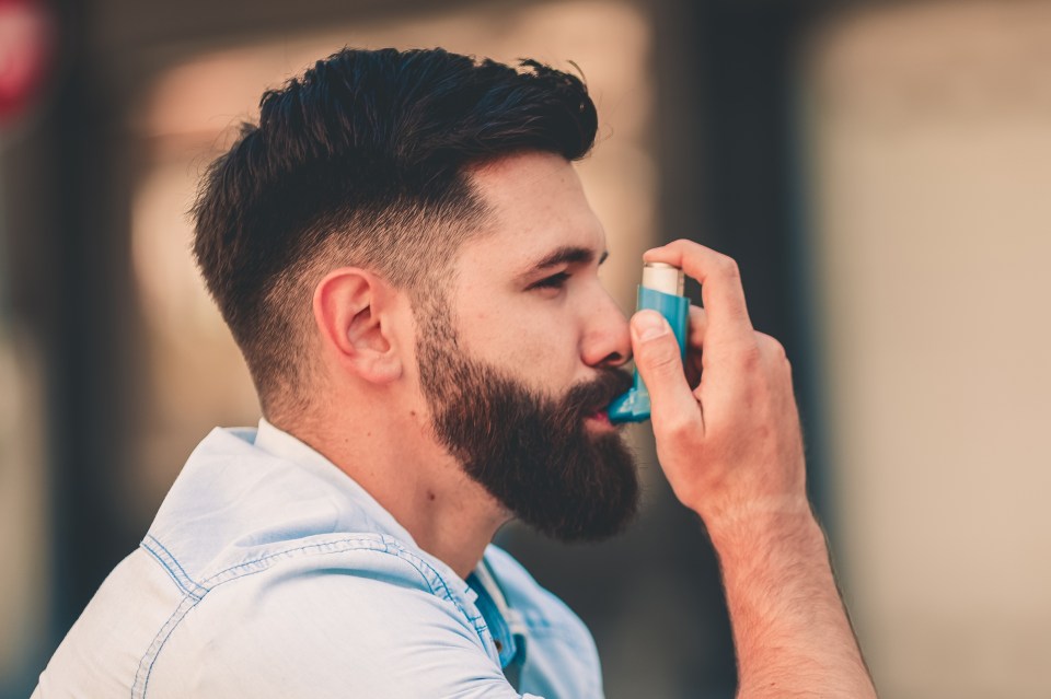 a man in a blue shirt is using an inhaler