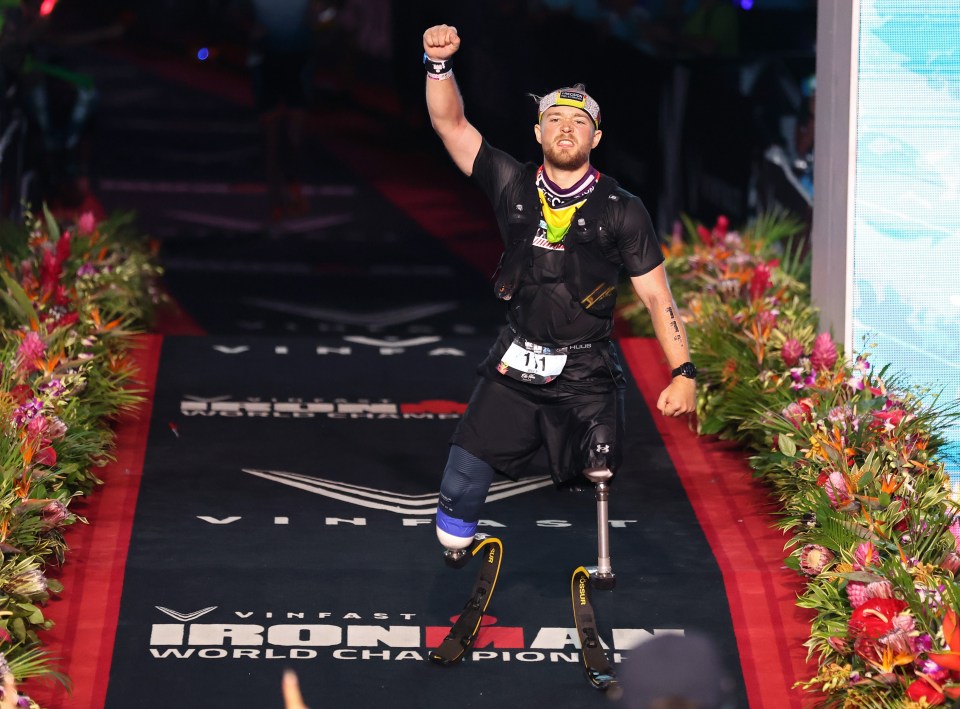 a man with prosthetic legs stands on a red carpet that says ironman world champion