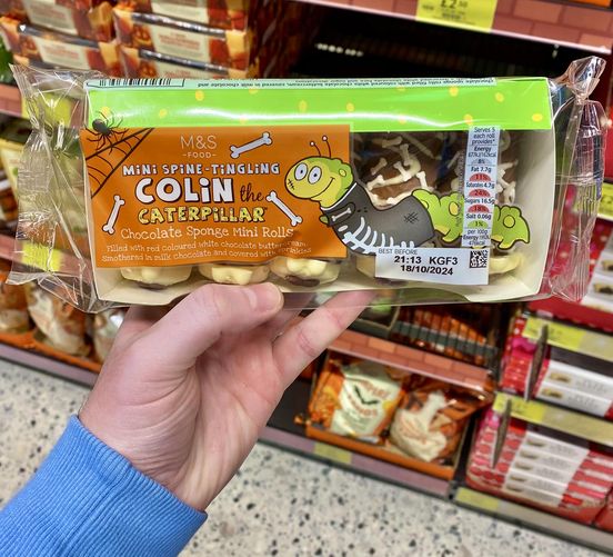 a person is holding a package of colin the caterpillar chocolate sponge mini rolls