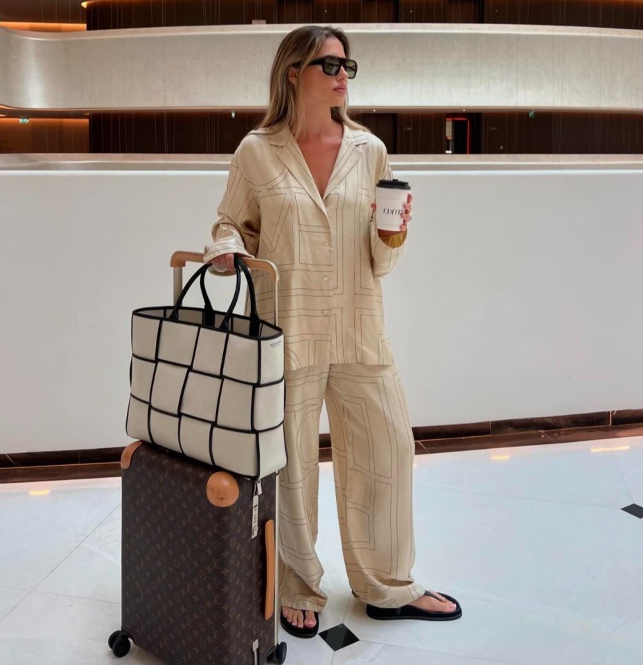 a woman standing in front of a building holding a cup of coffee