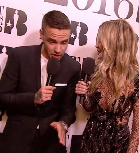 a man in a suit is talking into a microphone next to a woman in a black dress