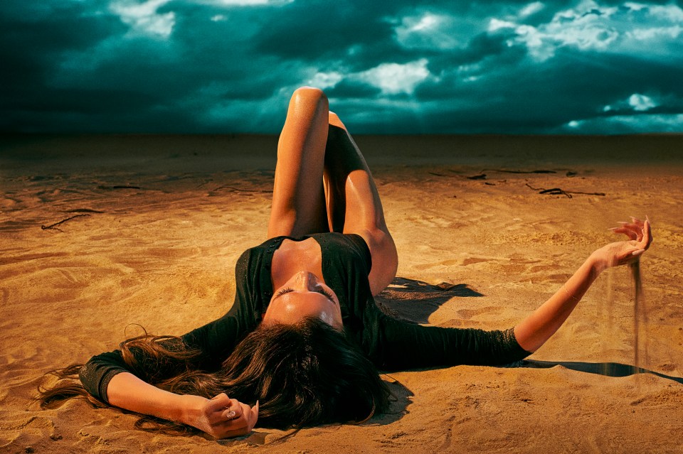 a woman laying in the sand with her arms outstretched