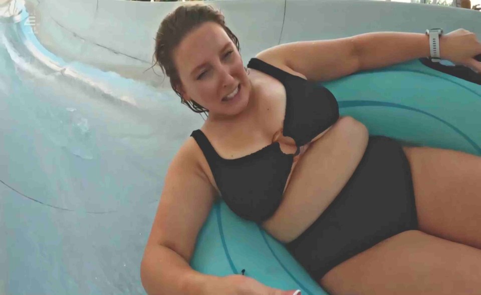 a woman in a black bikini is laying on a water slide