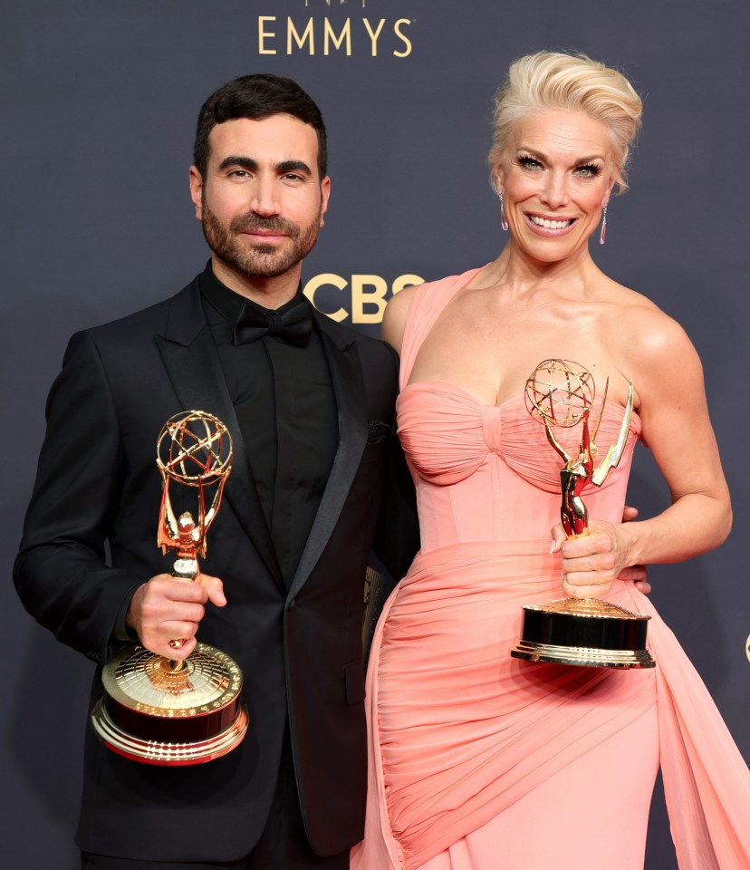 a man and a woman hold up their emmy awards