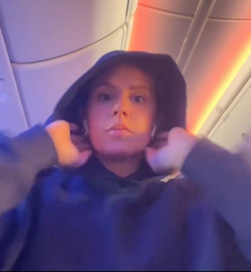 a woman wearing a hoodie on an airplane with the caption " saw a tiktok once of a girl saying she