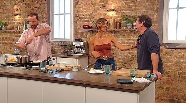 a man and a woman are standing in a kitchen talking to each other .