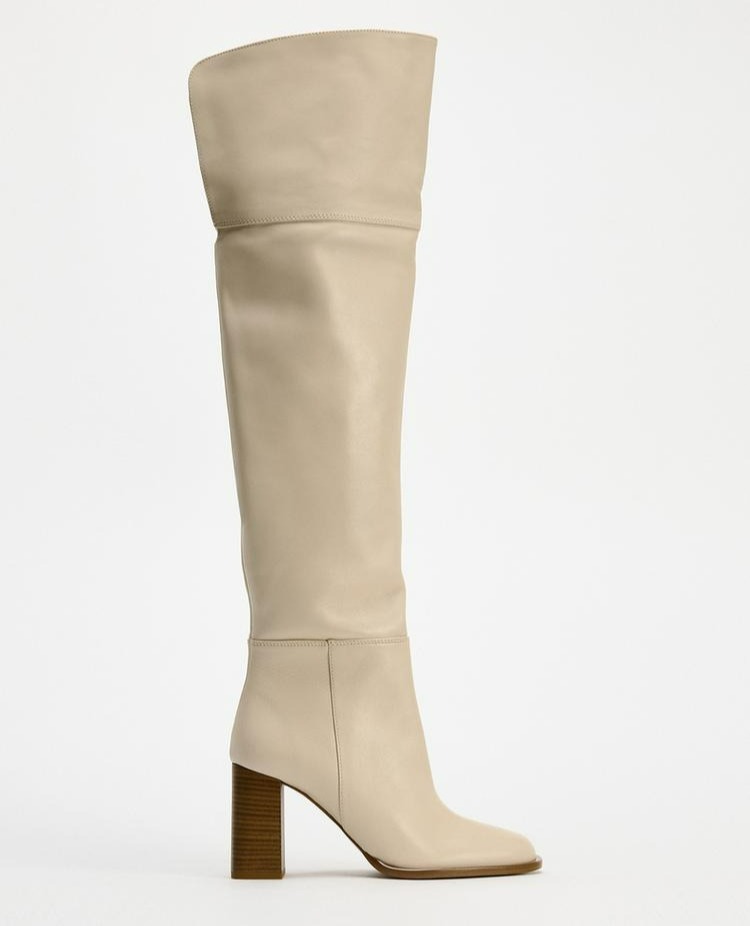 a pair of white knee high boots with a wooden heel