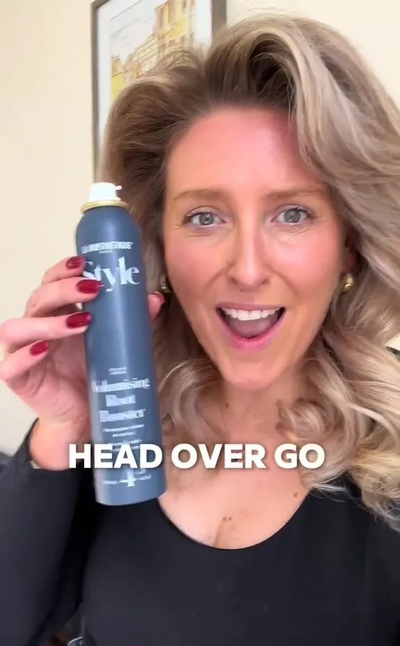 a woman is holding a bottle of style hair spray