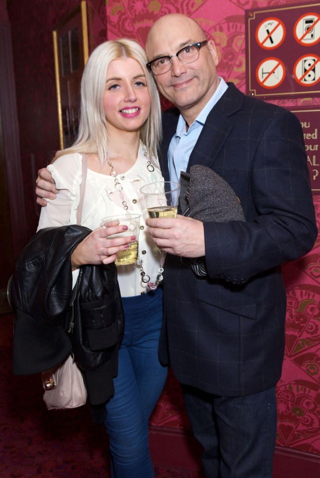 a man and a woman pose for a photo in front of a pink wall