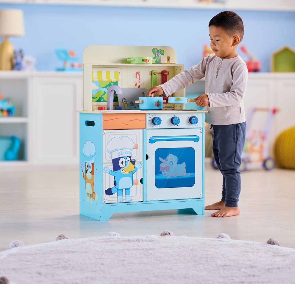 a little boy is playing with a blue and white kitchen set