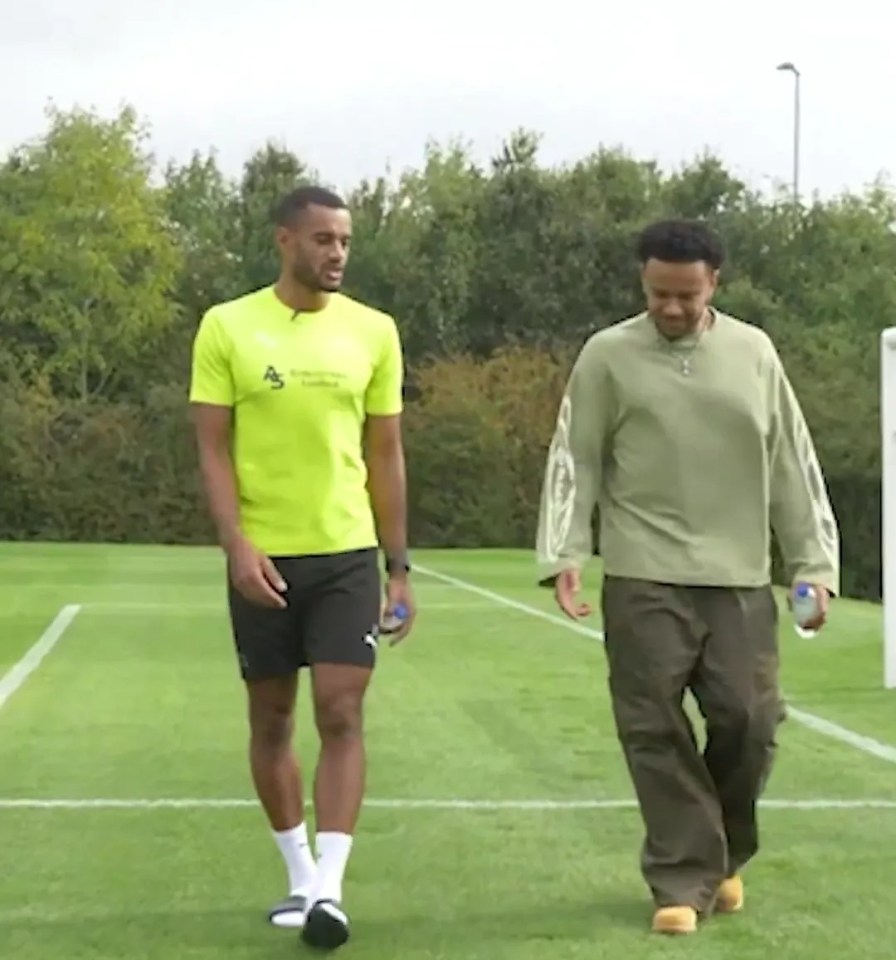 two men walking on a soccer field with one wearing a neon yellow shirt