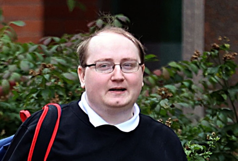 a man wearing glasses and a black sweater is walking down the street