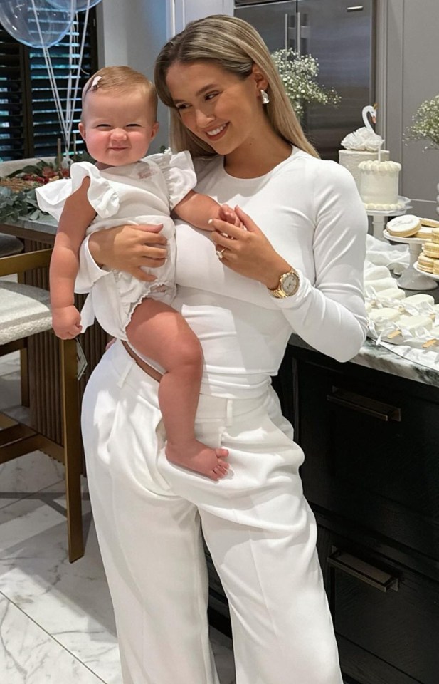 a woman holding a baby in a kitchen with balloons in the background