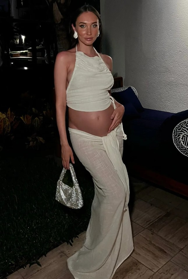 a pregnant woman in a white dress holds her belly