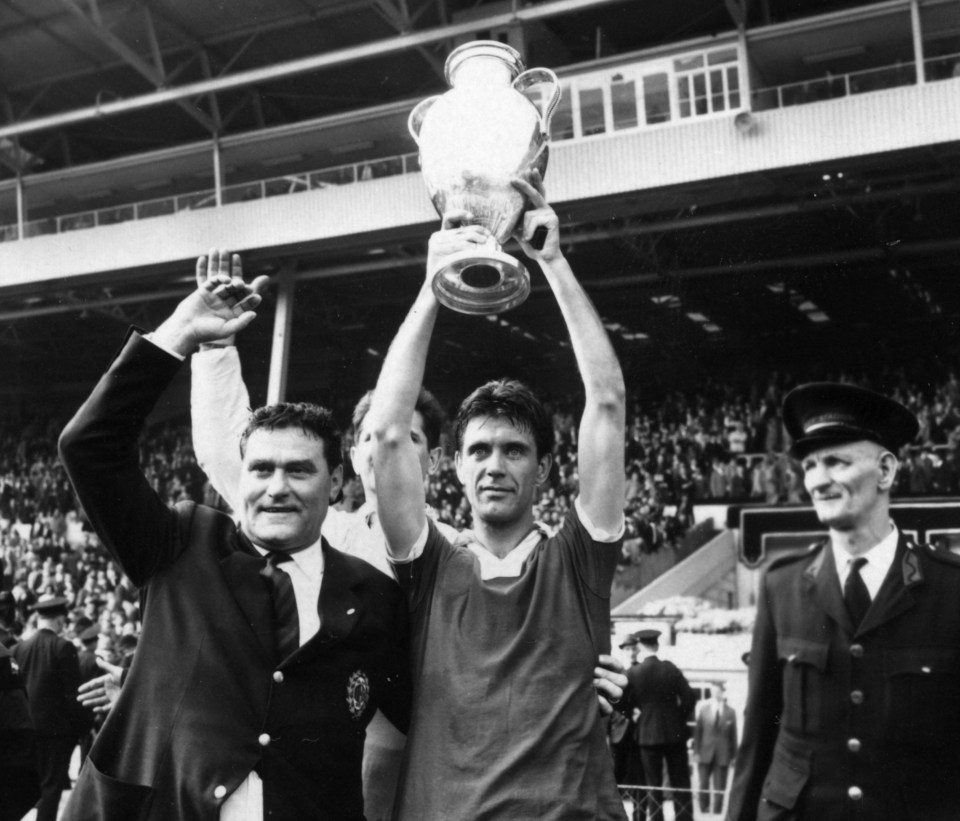 two men holding up a trophy in front of a crowd