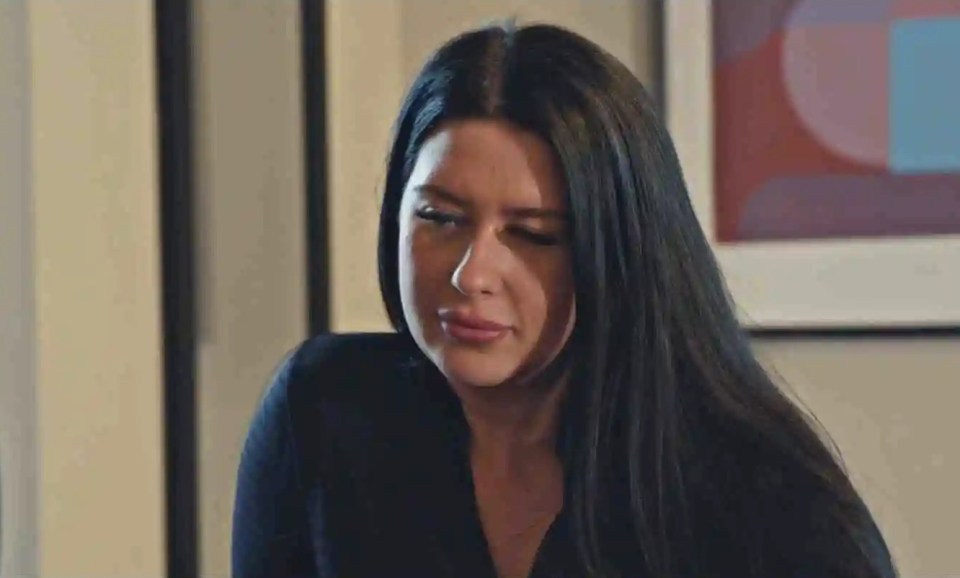 a woman with long dark hair is sitting in front of a framed picture