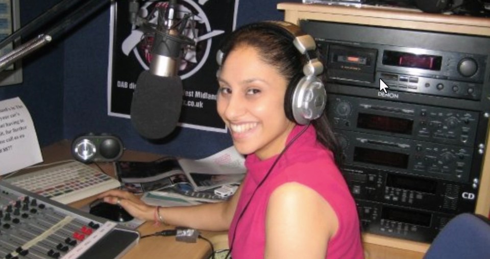 a woman wearing headphones sits in front of a microphone in a radio station