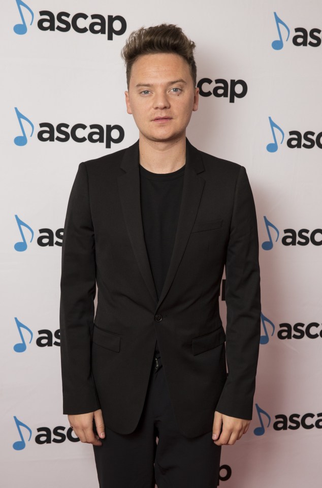 a man in a black suit stands in front of a wall that says ascap