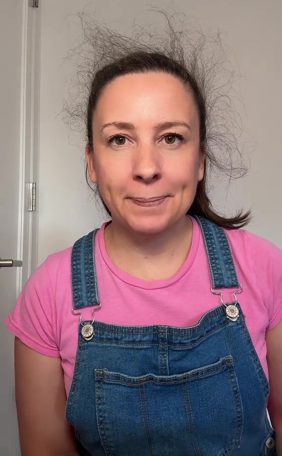 a woman wearing overalls and a pink shirt is smiling