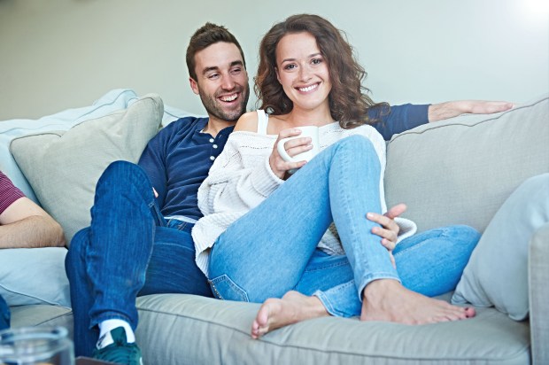 a man and a woman sit on a couch laughing