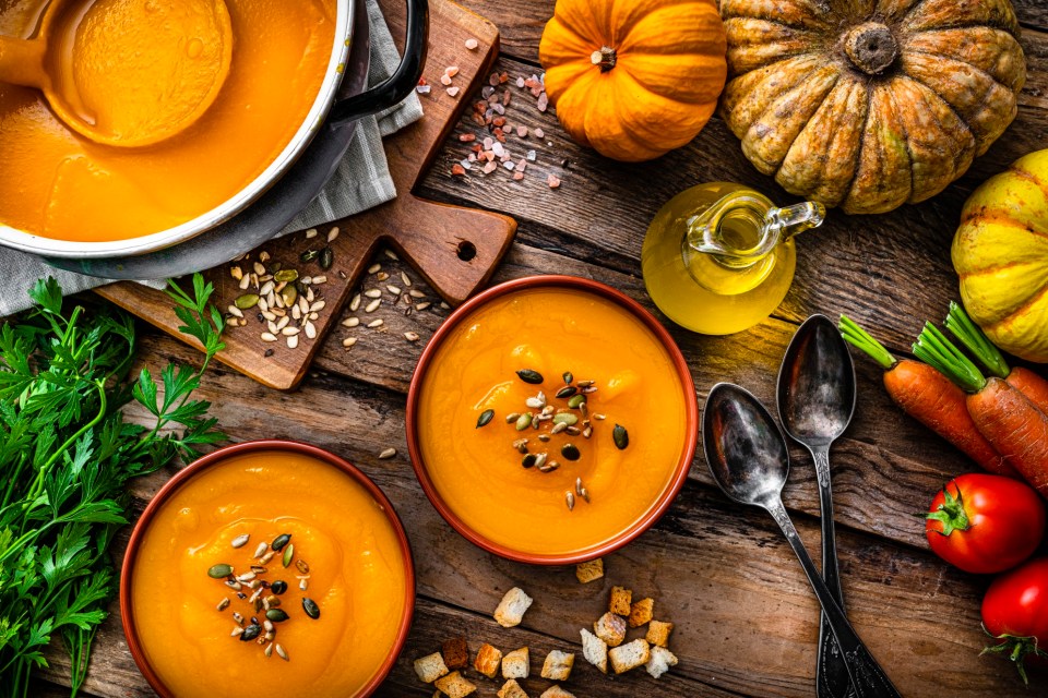 two bowls of pumpkin soup on a wooden table