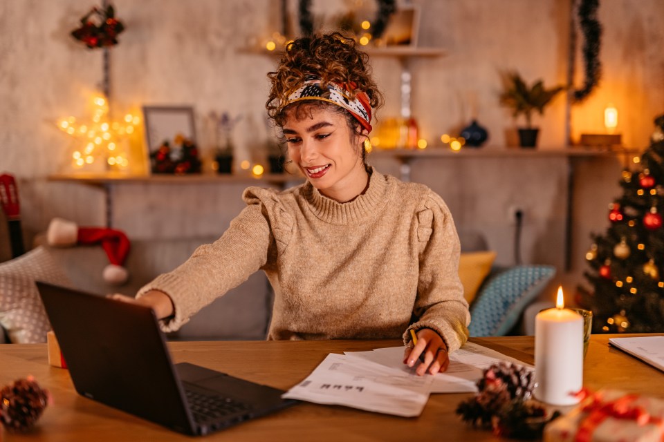 a woman sits at a table with a laptop and a candle in front of her