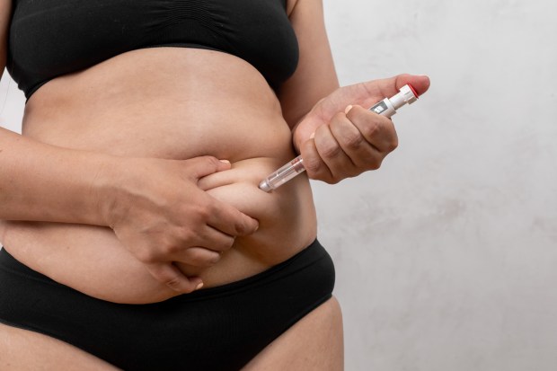 a woman in black underwear is holding an insulin pen