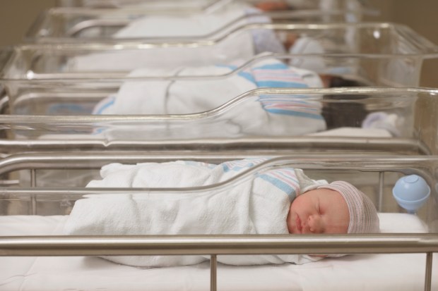 a baby wrapped in a white blanket is sleeping in a crib