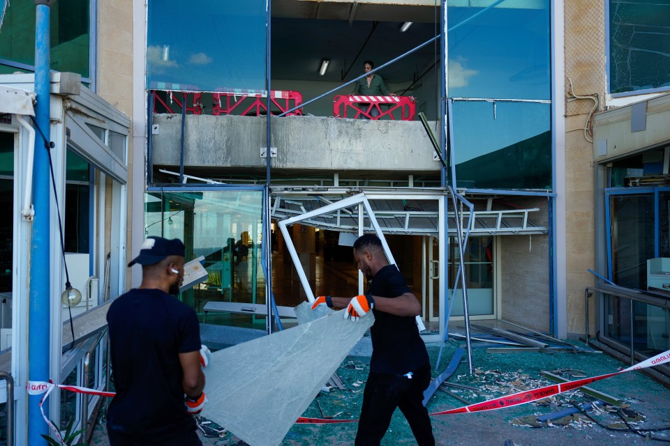 Workers remove broken glass from a damaged building that was hit during Iran's missile attack in Tel Aviv